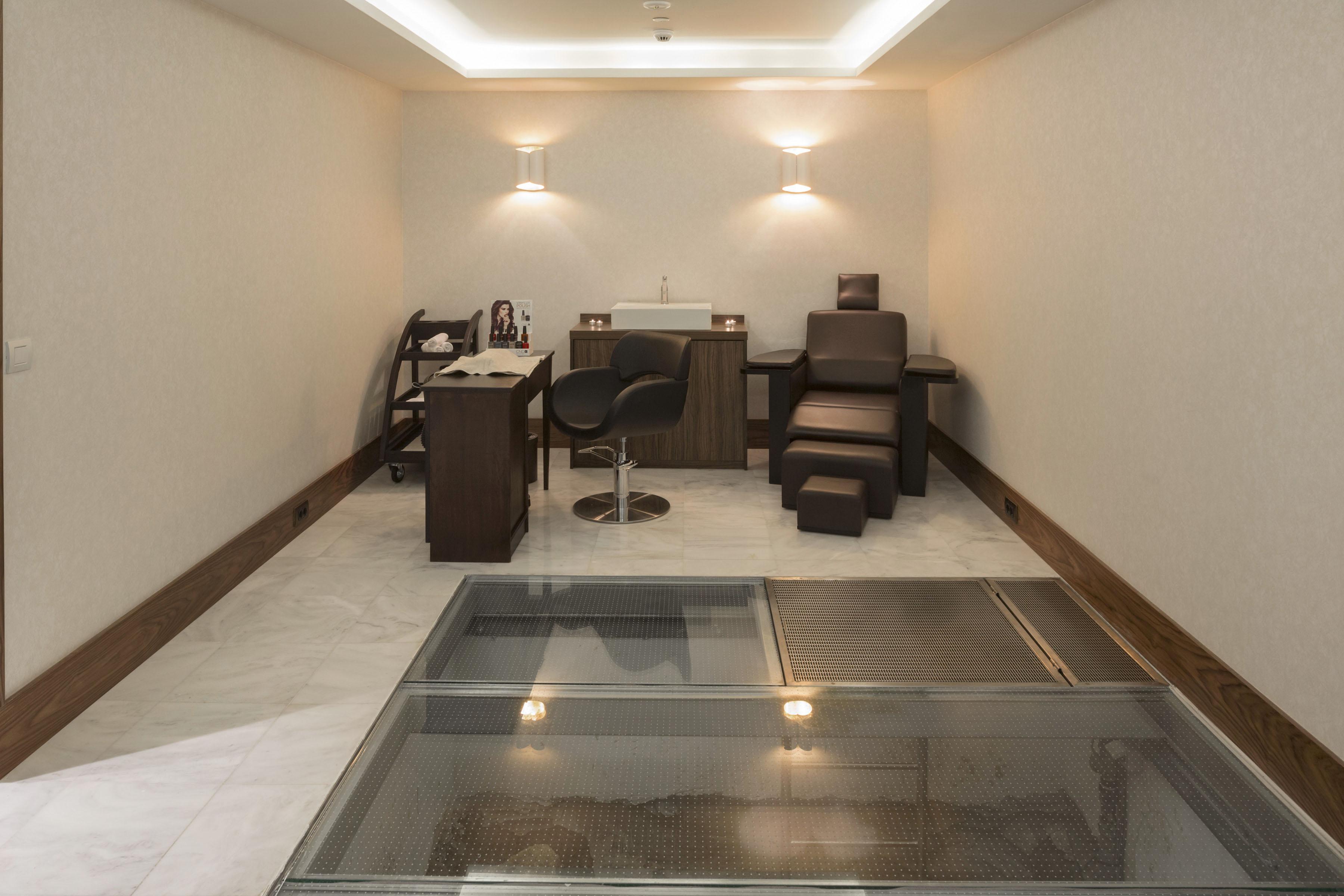 Electra Metropolis Hotell Athen Eksteriør bilde The photo shows a minimalistic room that appears to be designed for relaxation or therapy. It features a few key pieces of furniture: 

1. A desk with a stool, likely for a therapist or practitioner.
2. A reclining chair or lounge chair, providing a 